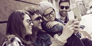 Viber blog hero - 4 Personen, die auf ein Smartphone gucken und lachen