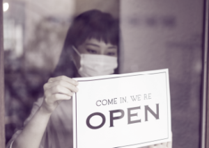 Asia-Pacific shop keeper holds store open sign