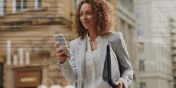 woman looking at her phone while walking in the city with overlay of financial graphs