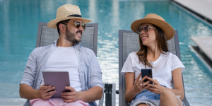 couple sits by pool with technology