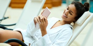 woman lounges in chair at a pool looking at phone